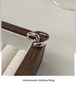 Macro shot of silver intertwined hollow ring on a wooden jewelry display stand