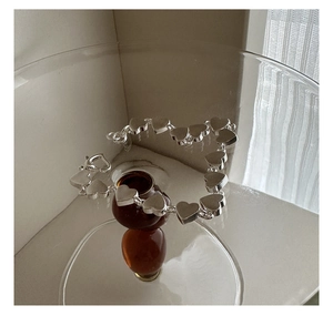 Macro detail of S925 sterling silver heart bracelet with matte finish in a glass cup
