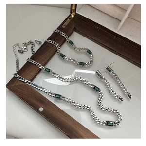 Macro detail of S925 silver Cuban chain jewelry set with emerald green zircon stones