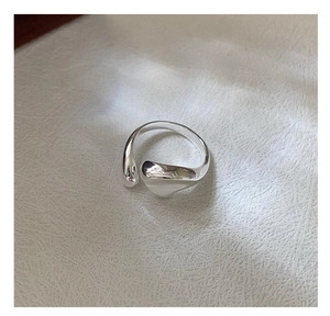 Detailed top view of a fluid S925 sterling silver open ring on woven fabric background