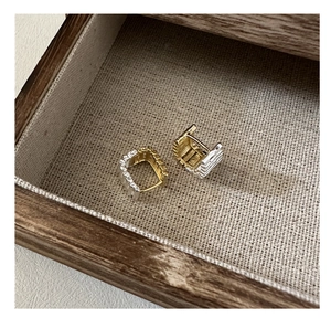 Dettaglio macro di orecchini quadrati in argento S925 con texture oro e argento