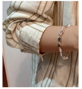Close-up of S925 sterling silver heart-shaped bracelet worn on a woman's wrist