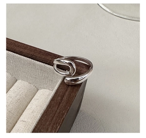Close-up of a S925 sterling silver U-shaped intertwined ring on a wooden tray