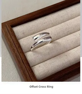 Macro detail of staggered crossed silver ring on elegant beige fabric jewelry tray