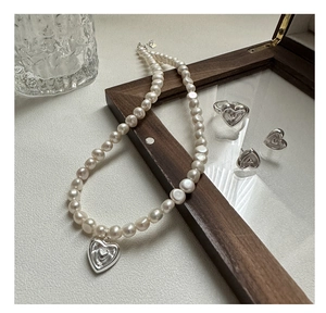 Détail de la parure de bijoux en perles avec collier à pendentif cœur, bague et boucles