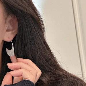 Elegant S925 sterling silver brushed crescent hoop earrings worn by a model in close-up