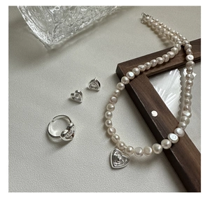 Parure bijoux trois pièces avec collier cœur, bague et boucles sur fond en bois