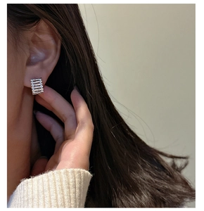 Dettaglio di un orecchino geometrico in argento S925 con strisce indossato da modella