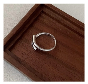 Detailed view of S925 sterling silver crossover ring on a rustic wooden tray