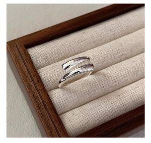 Detailed view of S925 sterling silver crossover ring displayed on a beige linen tray