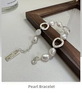 Baroque pearl bracelet featuring silver irregular rings and engraved metal pendant detail