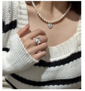Vue détaillée du collier de perles à cœur et de la bague cœur en argent sur un modèle
