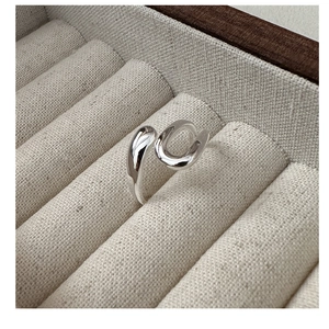 Macro shot of minimalist S925 sterling silver U-shaped ring on beige linen display