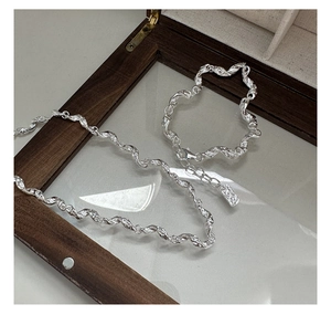 Detail shot of silver necklace and bracelet with molten texture on dark wood background