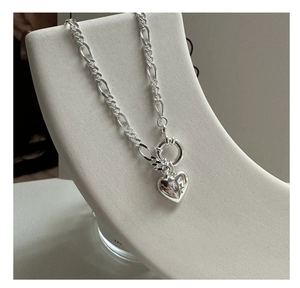Detailed shot of S925 silver heart pendant with star motif on a Figaro chain
