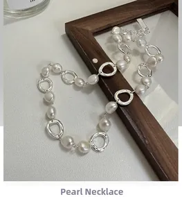 Detailed shot of baroque pearls and irregular silver links draped over a wood frame