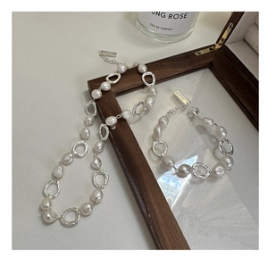 Detail of baroque freshwater pearl and silver link necklace set on a warm table