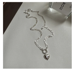 Macro view of silver Figaro chain featuring a heart pendant with an etched star detail