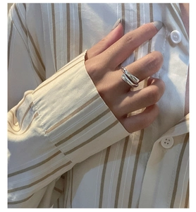 Detail of minimalist S925 sterling silver crossover ring worn on a finger