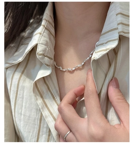 Macro shot of silver twisted wave necklace showing modern textured design on skin