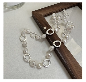 Macro shot of baroque pearl necklace with organic silver rings and lobster clasp detail