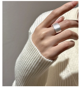 Gros plan d'une large bague carrée en argent S925 avec texture en métal brossé au doigt