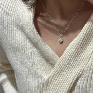 Detail of S925 sterling silver chain with organic pea pearl pendant on a model's neckline