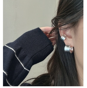 Macro detail of matte brushed silver C-shaped hoop earring on model with striped sweater
