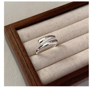 Macro shot of minimalist S925 sterling silver crisscross ring on beige fabric display