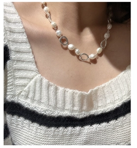Close-up of Baroque pearl necklace with silver oval rings worn by a fashion model