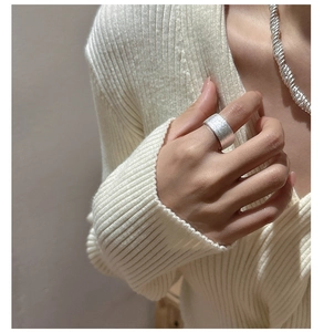 Gros plan détaillé d'une bague large en argent avec texture mate et finition brossée