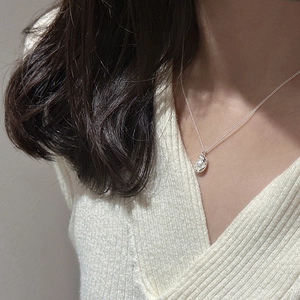 Detailed close-up of a silver pea pearl pendant necklace worn on a woman's collarbone