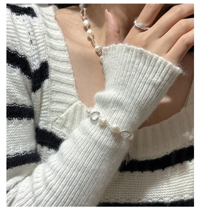Close-up of S925 silver pearl bracelet and matching ring on model with knit sweater
