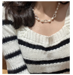Close-up of S925 silver irregular metal rings and freshwater pearls on a knitted sweater