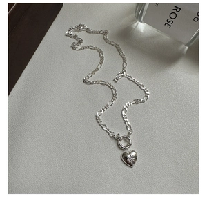 Detailed shot of S925 silver Figaro chain necklace with a star-engraved heart pendant and OT clasp