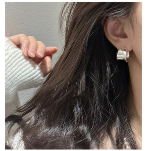 Close-up of minimalist silver wide hoop earring with polished mirror finish on model