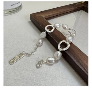 Macro detail of irregular pearl bracelet with liquid metal rings and engraved tag