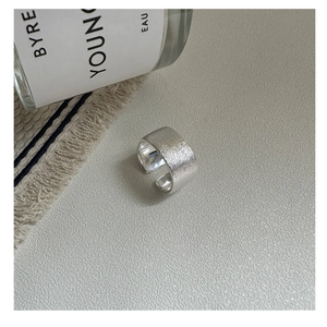 Détail macro d'une bague large argentée minimaliste avec surface à texture brossée
