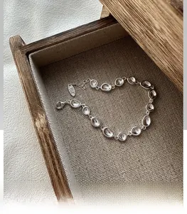 Makroaufnahme von S925 Sterlingsilber Bohnenarmband mit klarem Stein auf Leinen