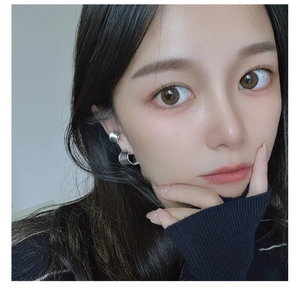 Close-up of minimalist matte silver C-shaped earring worn by a model in soft light