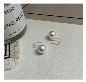 Detailed close-up of matte silver ball earrings with unique J-hook minimalist design