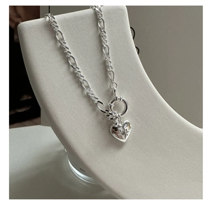Detail of S925 sterling silver puffed heart pendant with starburst engraving on Figaro chain