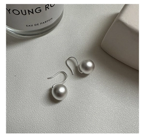 Macro detail of S925 sterling silver frosted ball earrings with a minimalist matte finish