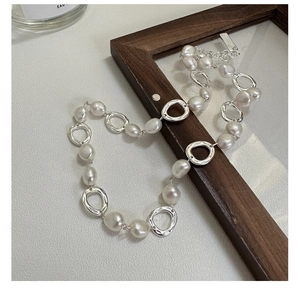 Detailed close-up of S925 sterling silver chain with irregular baroque pearls on wood