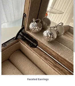 Detailed close-up of faceted S925 sterling silver hoop earrings in a wooden jewelry box