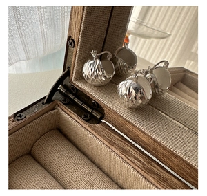 Close-up of S925 sterling silver diamond-cut hoop earrings in a vintage wooden jewelry box