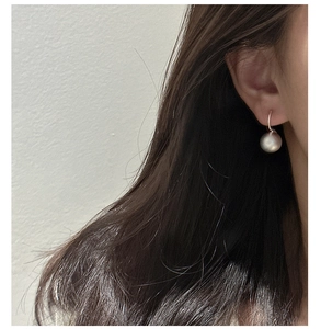 Close-up of a model wearing minimalist silver frosted ball earrings with a sleek metal hook