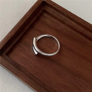 Minimalist S925 sterling silver crossover open ring on a dark wooden tray