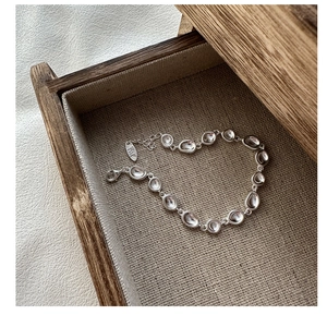 Detail eines unregelmäßigen S925 Sterling Silber Armbands mit Karabiner auf Leinenstruktur