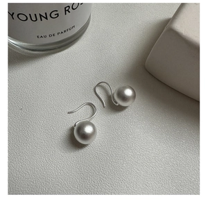 Macro view of matte silver round bead earrings on a textured minimalist background